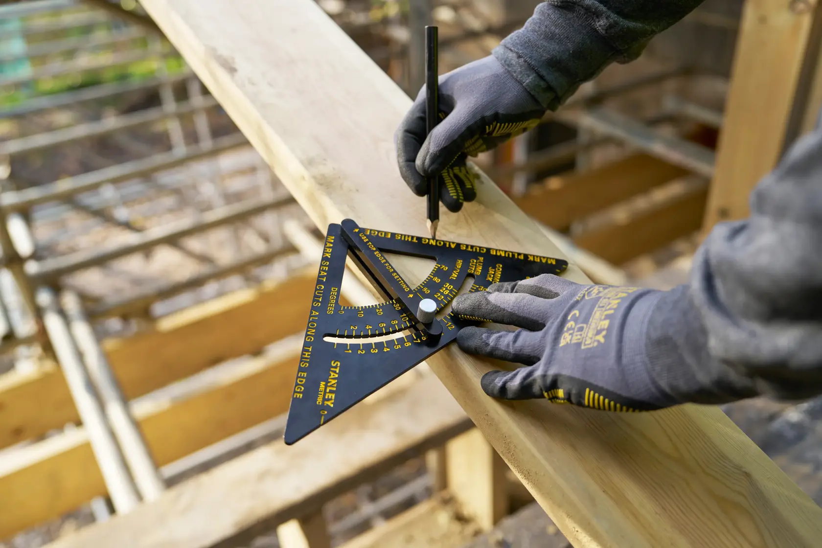 Foto des STANLEY STHT46056-0 Zimmermannswinkels im Einsatz auf Holzbrett, Arbeiter mit Handschuhen markiert das Holz.