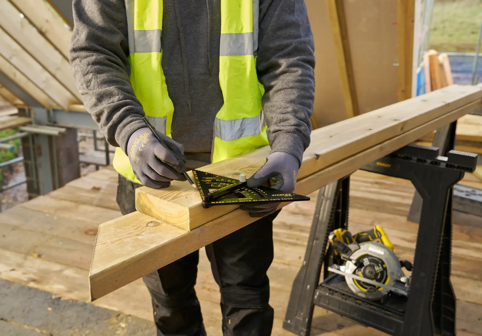 STANLEY STHT46056-0 Zimmermannswinkel auf Holzbalken, schräge Ansicht, vom Arbeiter für präzises Anzeichnen auf Baustelle verwendet.