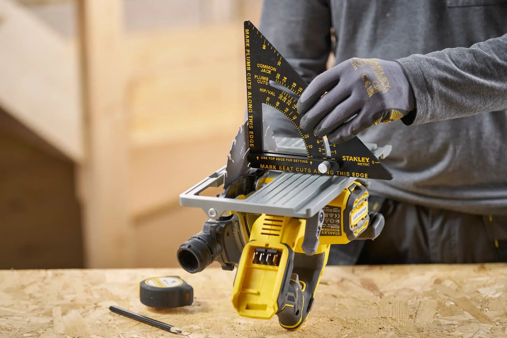 STANLEY STHT46056-0 Zimmermannswinkel im Einsatz, misst den Sägewinkel auf einem Werktisch mit Maßband und Bleistift.