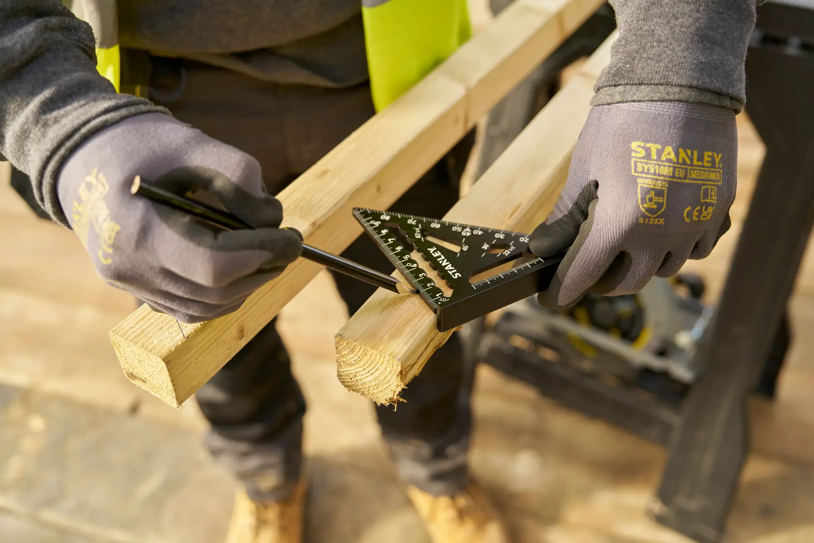 STANLEY STHT46100-0 Dachdeckerwinkel beim Messen und Anzeichnen eines Holzbalkens, Arbeiter mit Handschuhen.