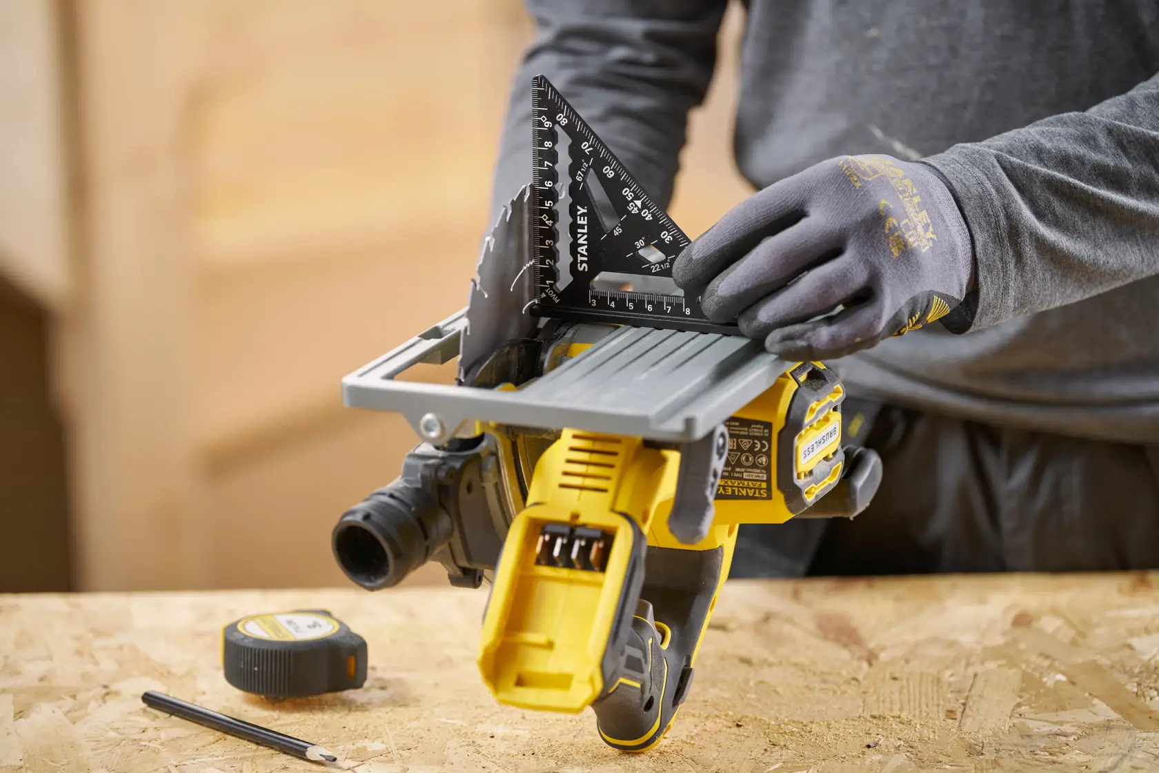 STANLEY STHT46100-0 schwarzes Zimmermannswinkel in behandschuhter Hand auf Werkbank, Aufsicht.