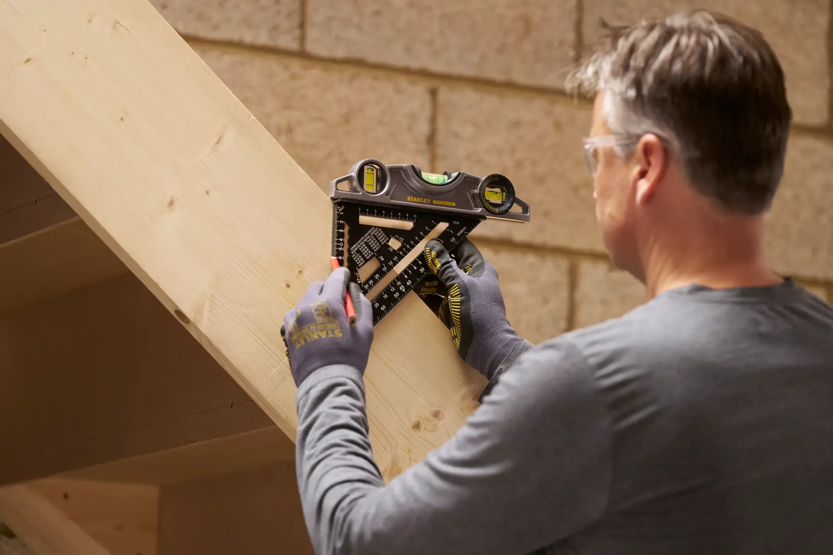 STANLEY STHT46101-0 Kombinationswinkel, von einer Person zum Anzeichnen auf einem Holzbalken verwendet.