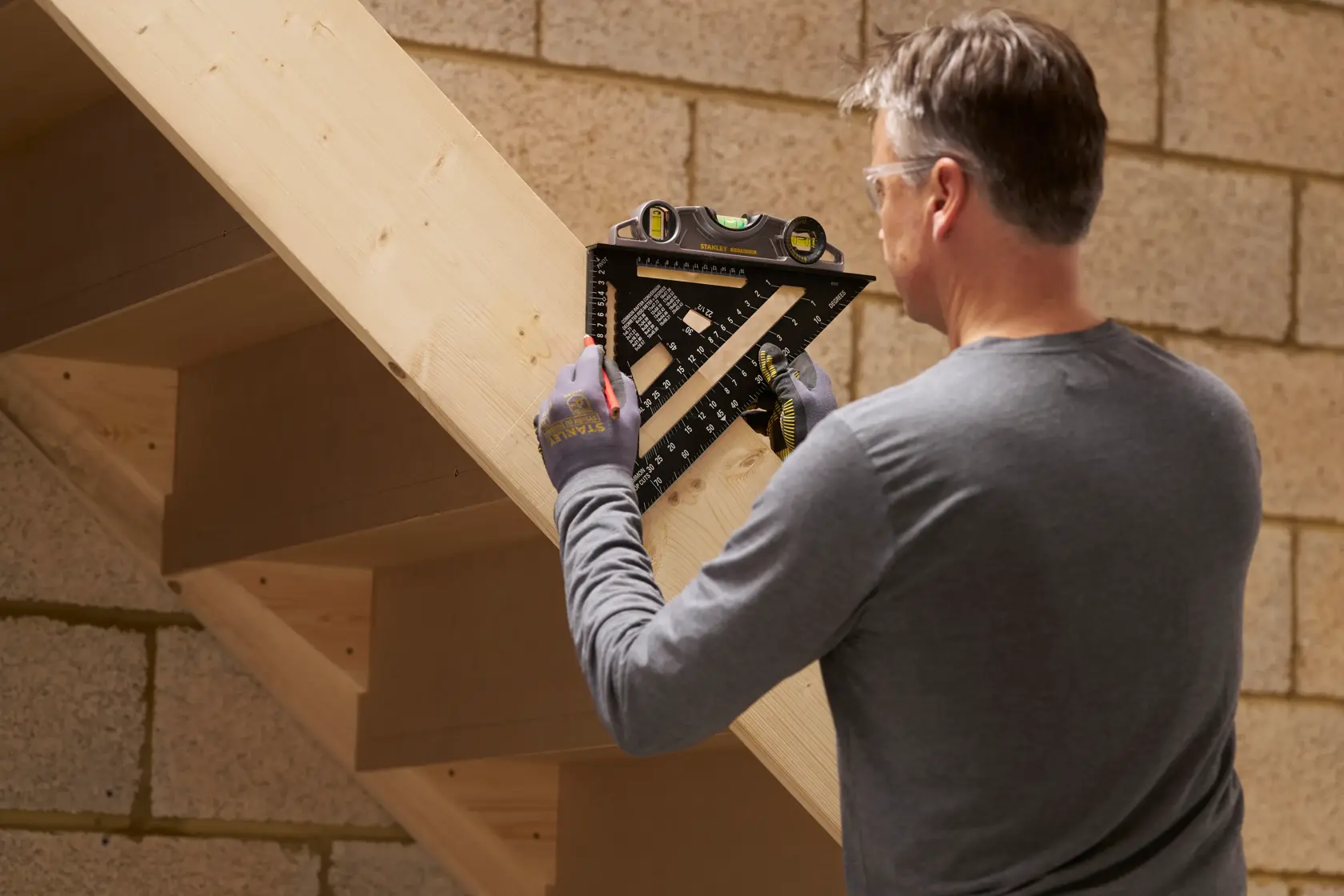 Handwerker benutzt STANLEY STHT46102-0 schwarzen Winkel mit Wasserwaage an hölzerner Treppe.