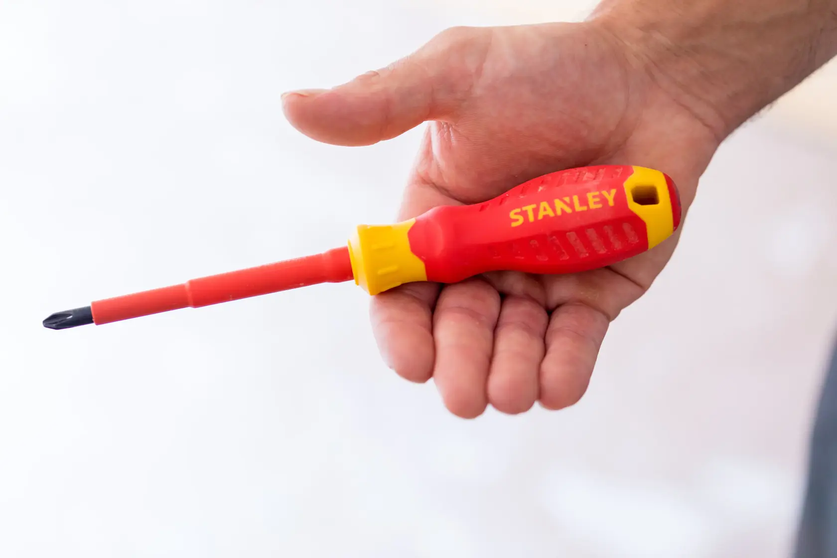 Foto von STANLEY STHT60030-0 rotem und gelbem isoliertem Schraubendreher in der Hand gehalten.