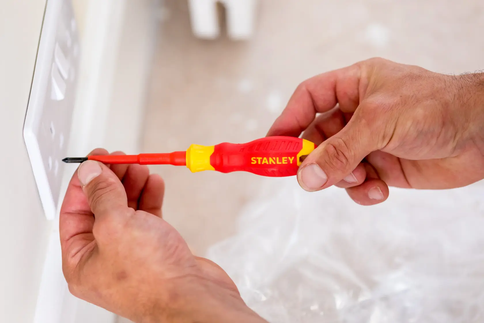 STANLEY STHT60032-0 isolierter Schraubendreher mit rot-gelbem Griff an Wandsteckdose.