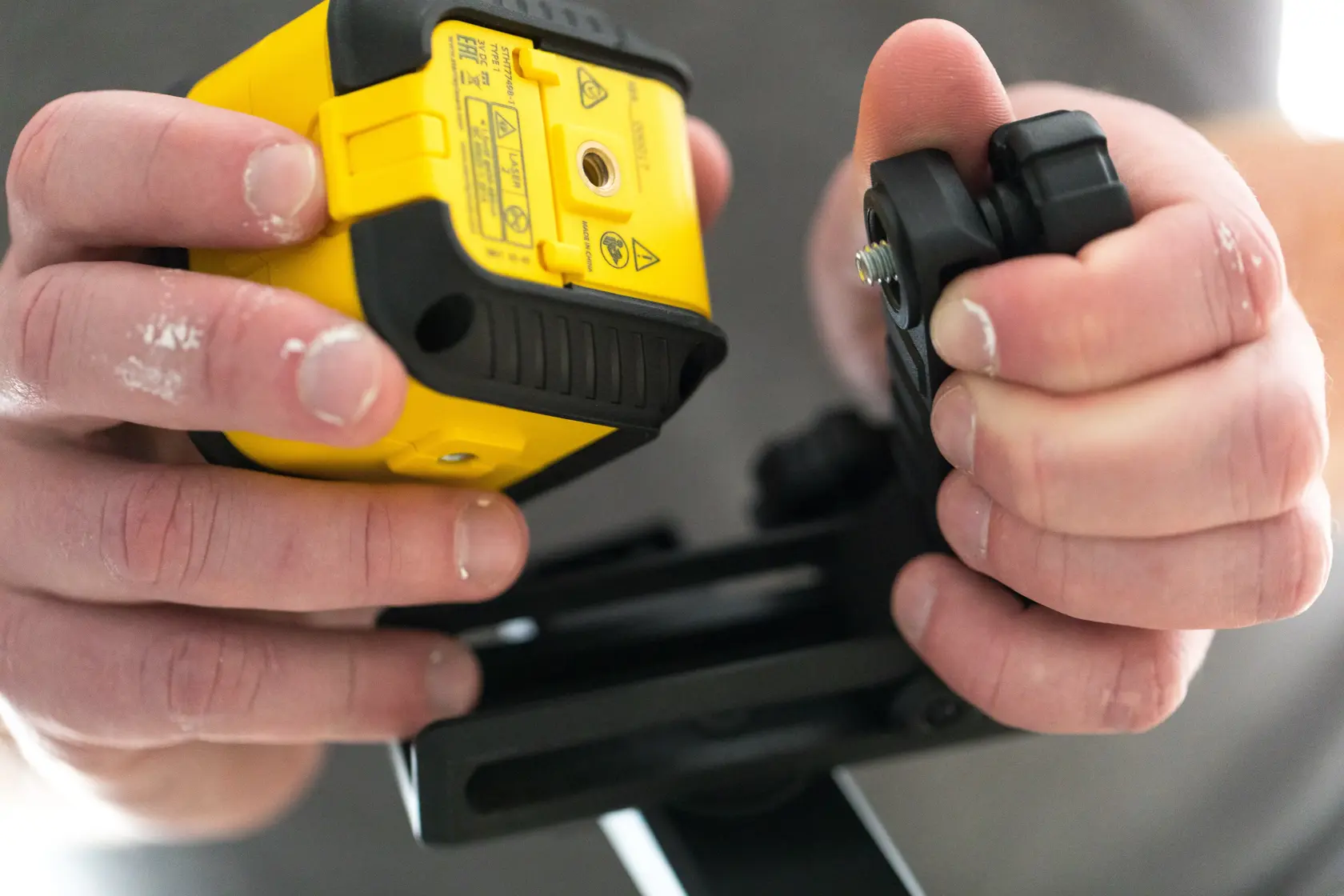 Foto vom STANLEY STHT77499-1 Laser-Nivelliergerät in der Hand, Montage auf Stativ, Nahaufnahme.