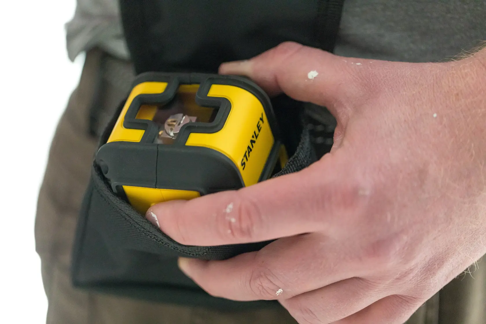 STANLEY STHT77499-1 gelber Laser-Nivellierer im Werkzeugbeutel, Nahaufnahme, von Hand gehalten.