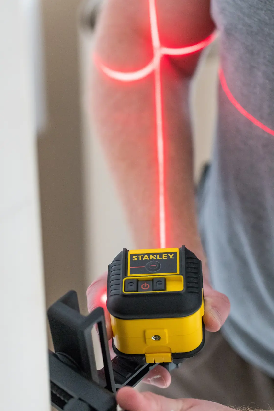 STANLEY STHT77502-1 Laser-Nivelliergerät projiziert rote Linien, in Hand gehalten, Nahaufnahme.