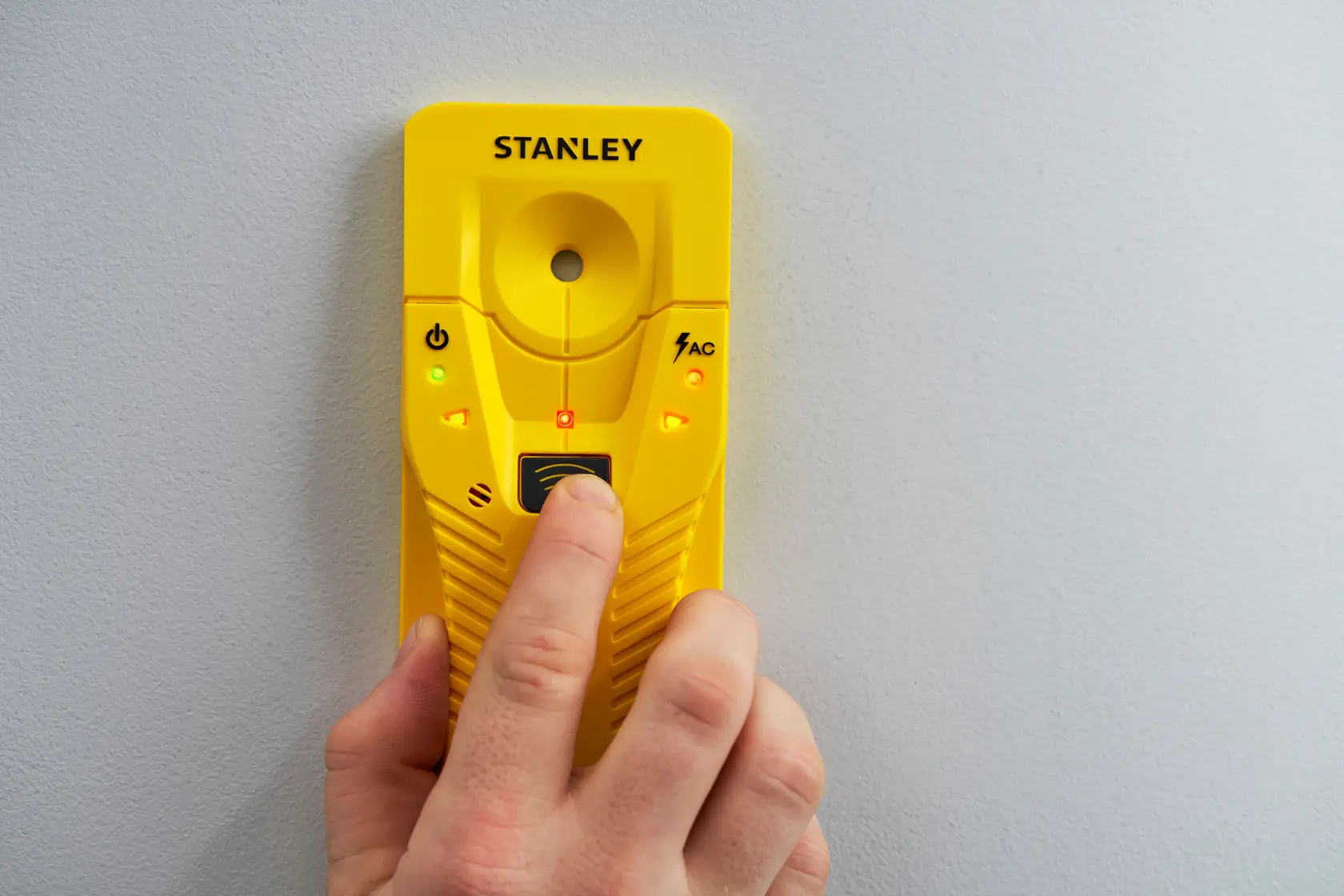 STANLEY STHT77587-0 gelber Balkendetektor an der Wand, Frontansicht, Leuchten eingeschaltet.