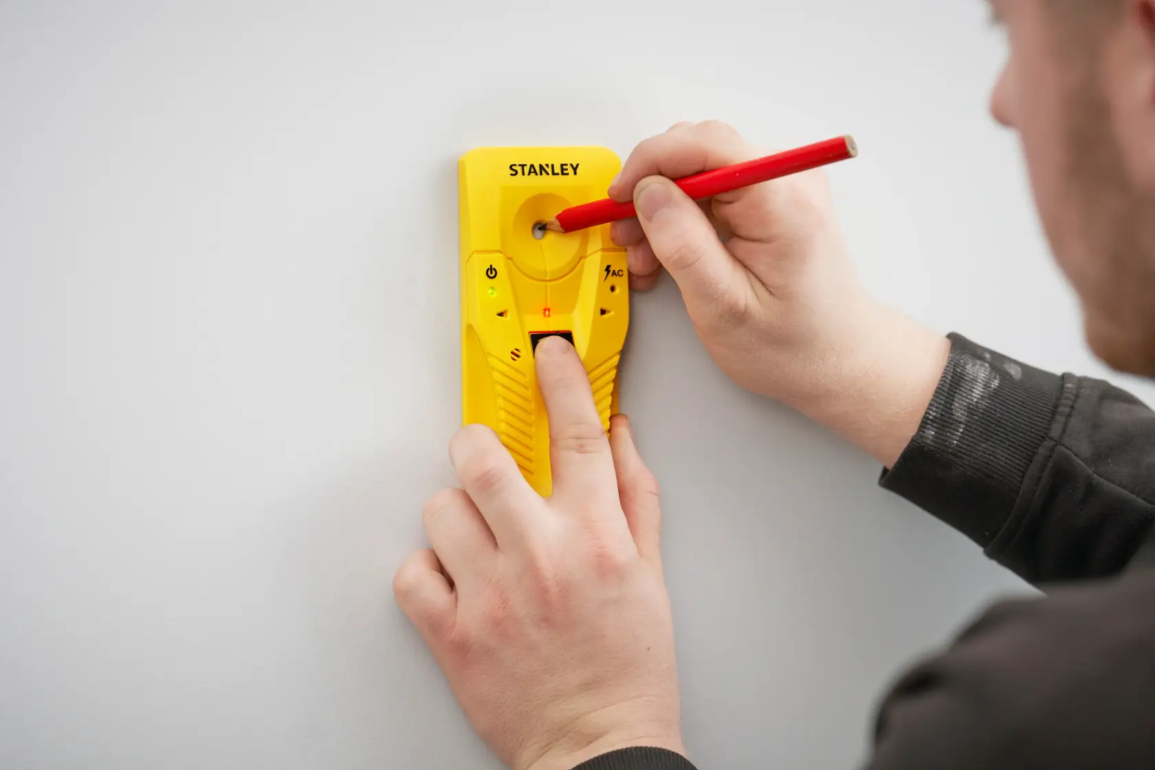STANLEY STHT77587-0 gelber Leitungsfinder an der Wand, Nutzer markiert Stelle mit rotem Bleistift.