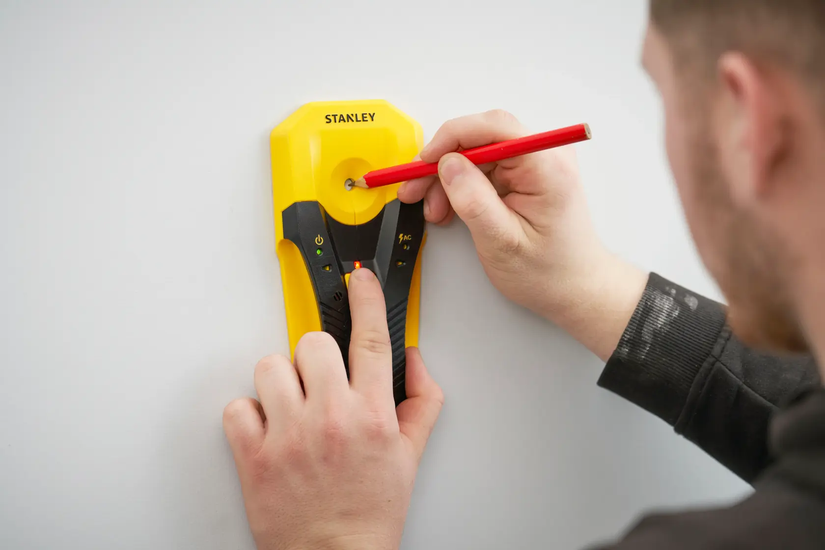 STANLEY STHT77588-0 Ortungsgerät an Wand, roter Bleistift markiert die Mitte, Nahaufnahme Fotografie.