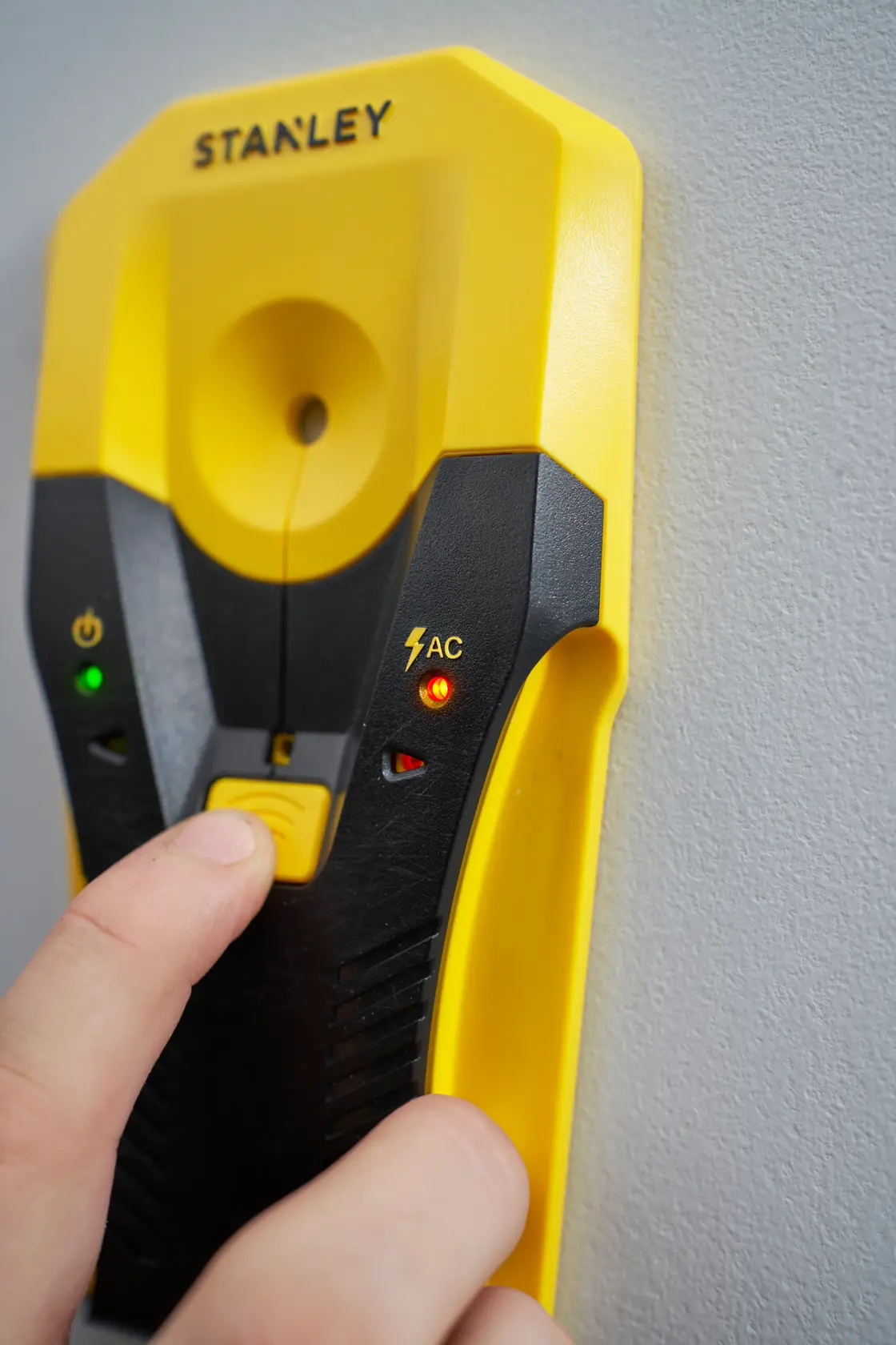 Fotografie des STANLEY STHT77588-0 digitalen Ortungsgeräts, gelb-schwarz mit Kontrollleuchten, an einer Wand.