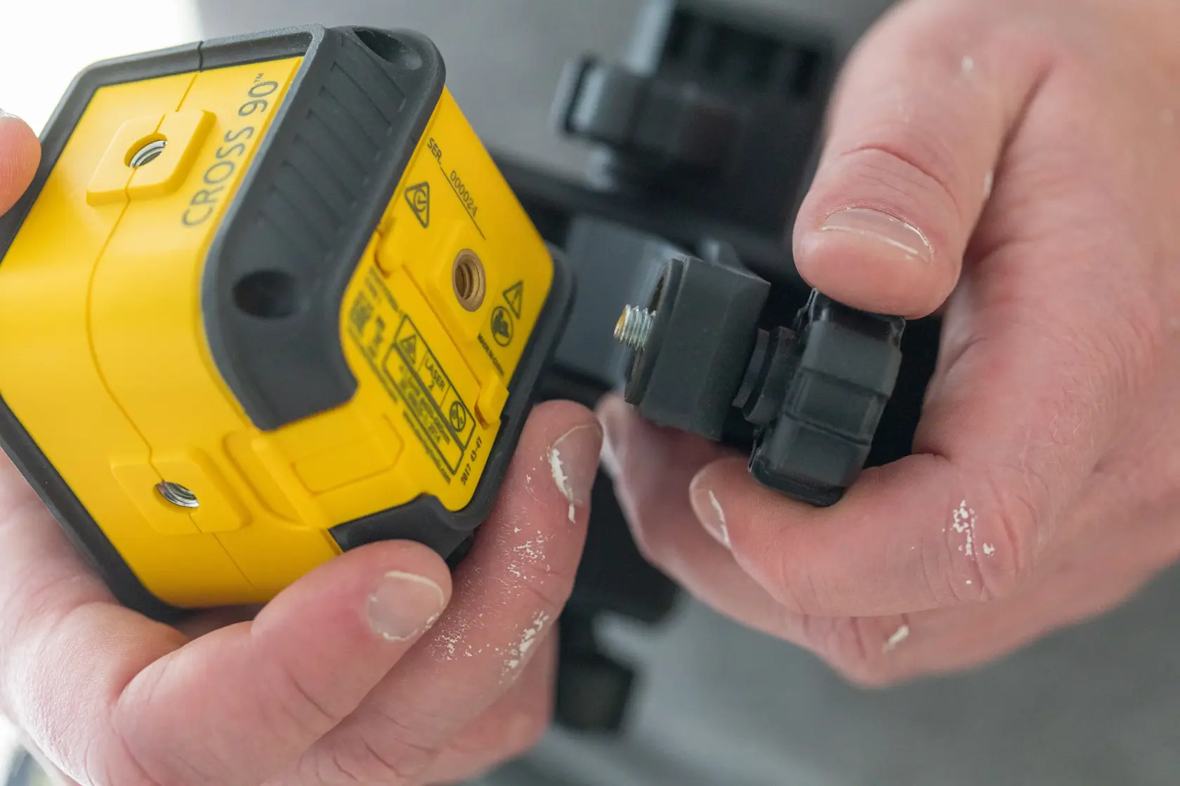 STANLEY STHT77592-1 gelber Kreuzlinienlaser wird an Halterung befestigt, Nahaufnahme.