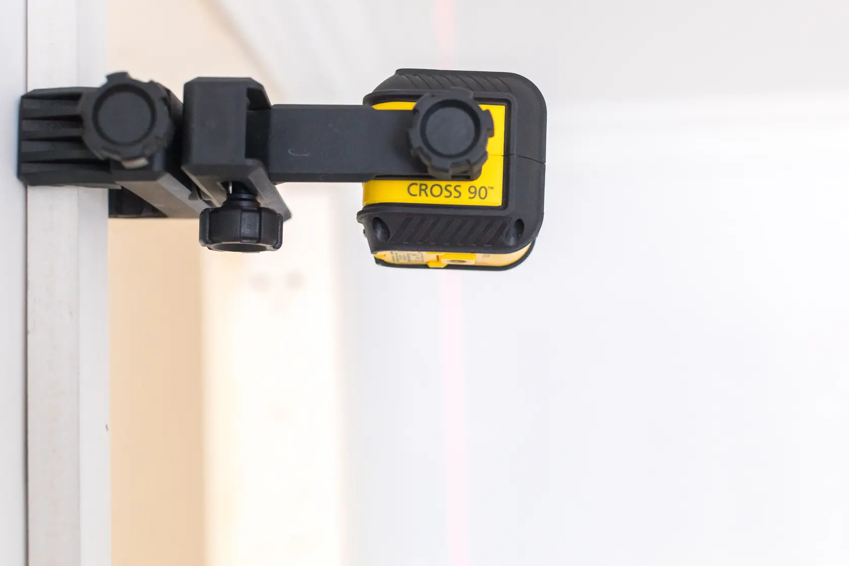 STANLEY STHT77592-1 Kreuzlinien-Laser auf Wand montiert, Seitenansicht, gelbes und schwarzes Gehäuse.