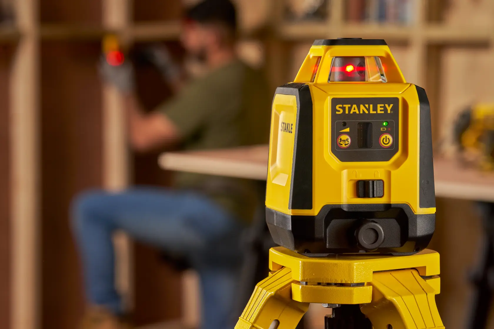 Foto des STANLEY STHT77616-0 Laser-Nivelliergeräts auf Stativ in Werkstattumgebung.