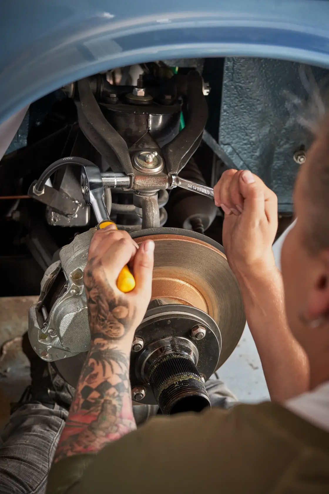 STANLEY STMT82672-0 Ratschen- und Steckschlüsselsatz am Auto-Bremsenmontage, Nahaufnahme, Person arbeitet.
