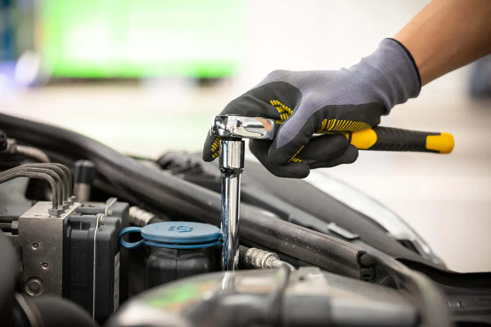 STANLEY STMT86006-0 Umschaltknarre bei Motorwartung, Nahaufnahme einer behandschuhten Hand mit Werkzeug.