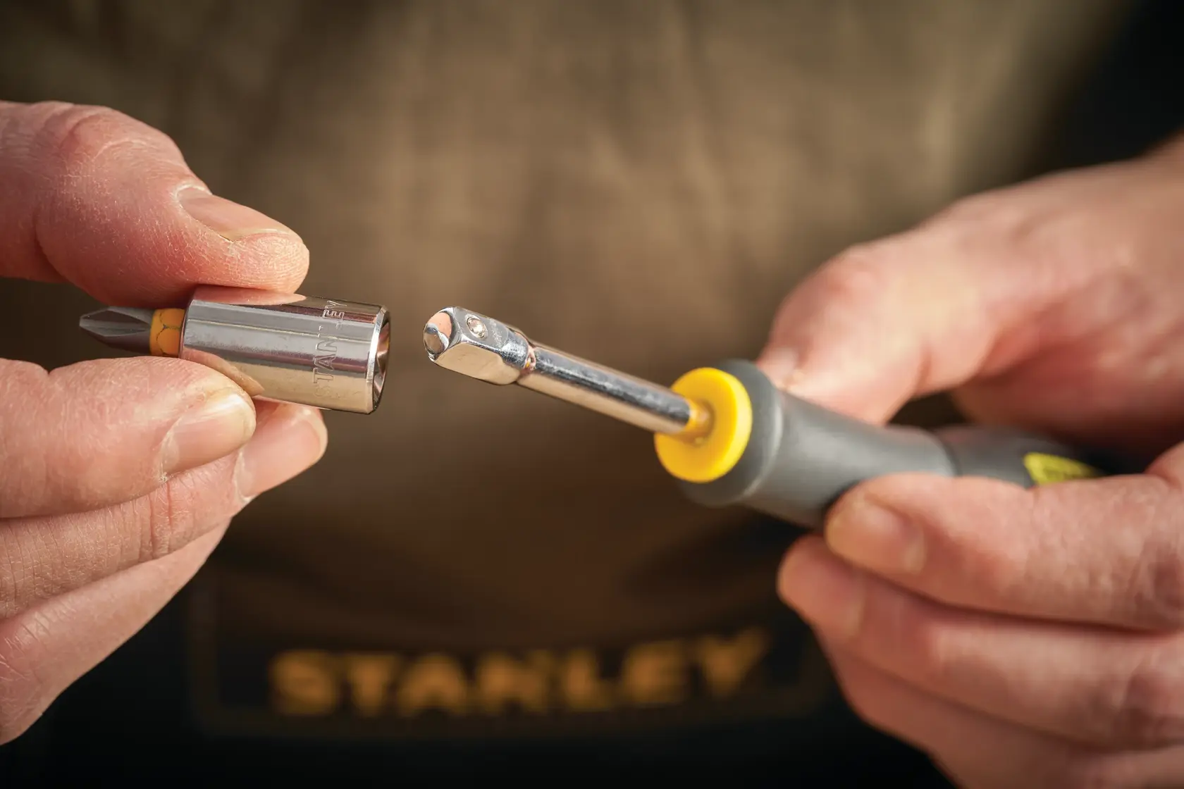 STANLEY STMT86124-0 Hand hält Ratschen-Schraubendreher und Stecknussbit im Nahaufnahme.