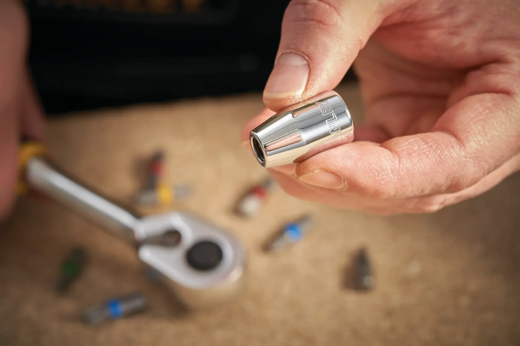 Foto von STANLEY STMT86250-0 Steckschlüssel in Hand, Ratsche und Bits im Hintergrund.