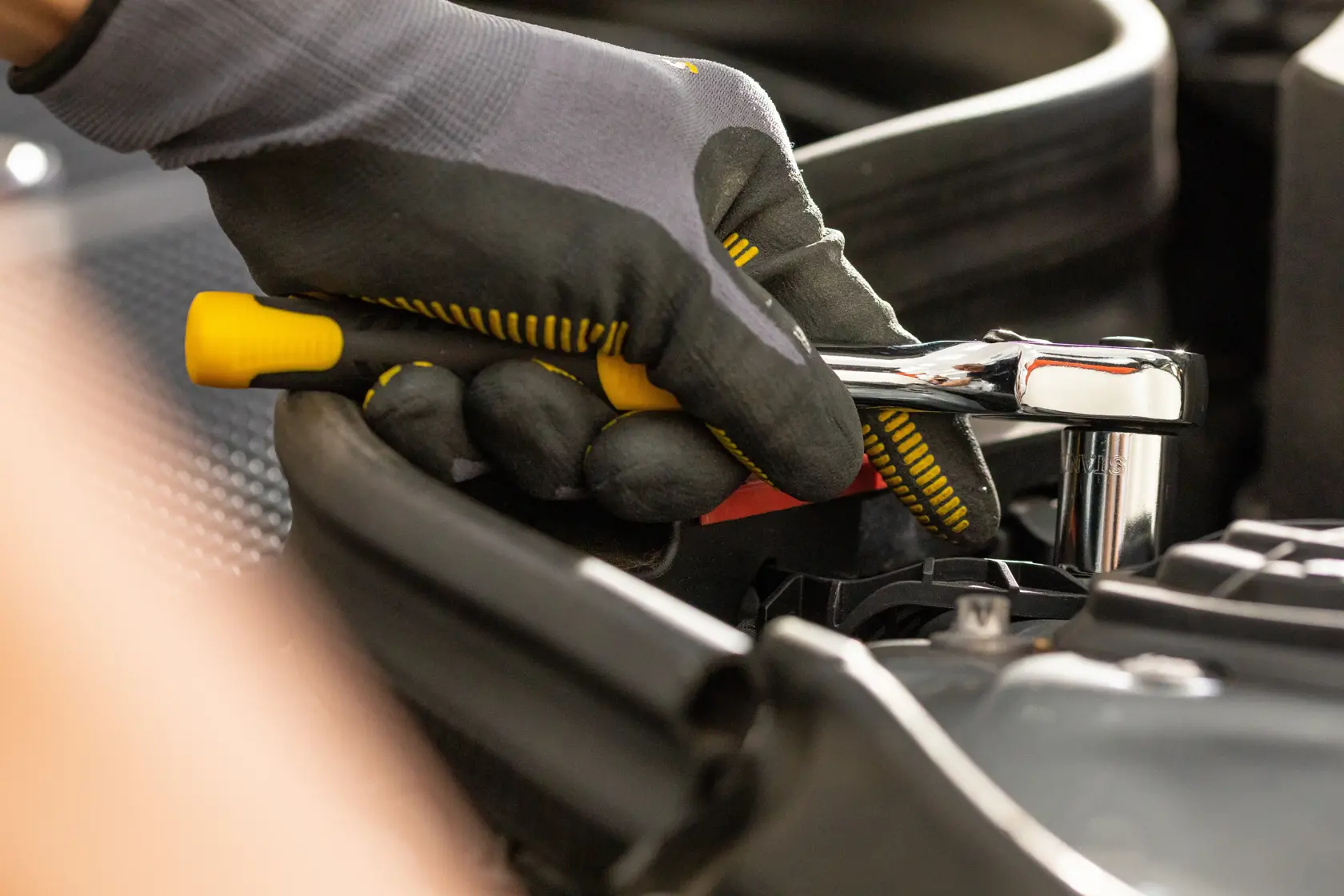 STANLEY STMT86305-0 Ratschen-Schlüssel im Einsatz, Nahaufnahme im Automobilbereich, gelb-schwarzer Griff.