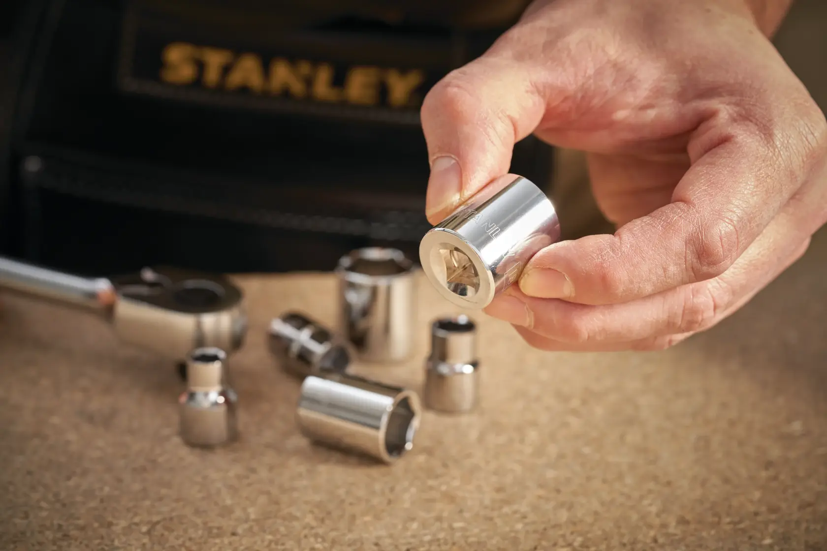 STANLEY STMT86311-0 Steckschlüsselsatz, silberne Stecknüsse auf Tisch, Hand hält eine.