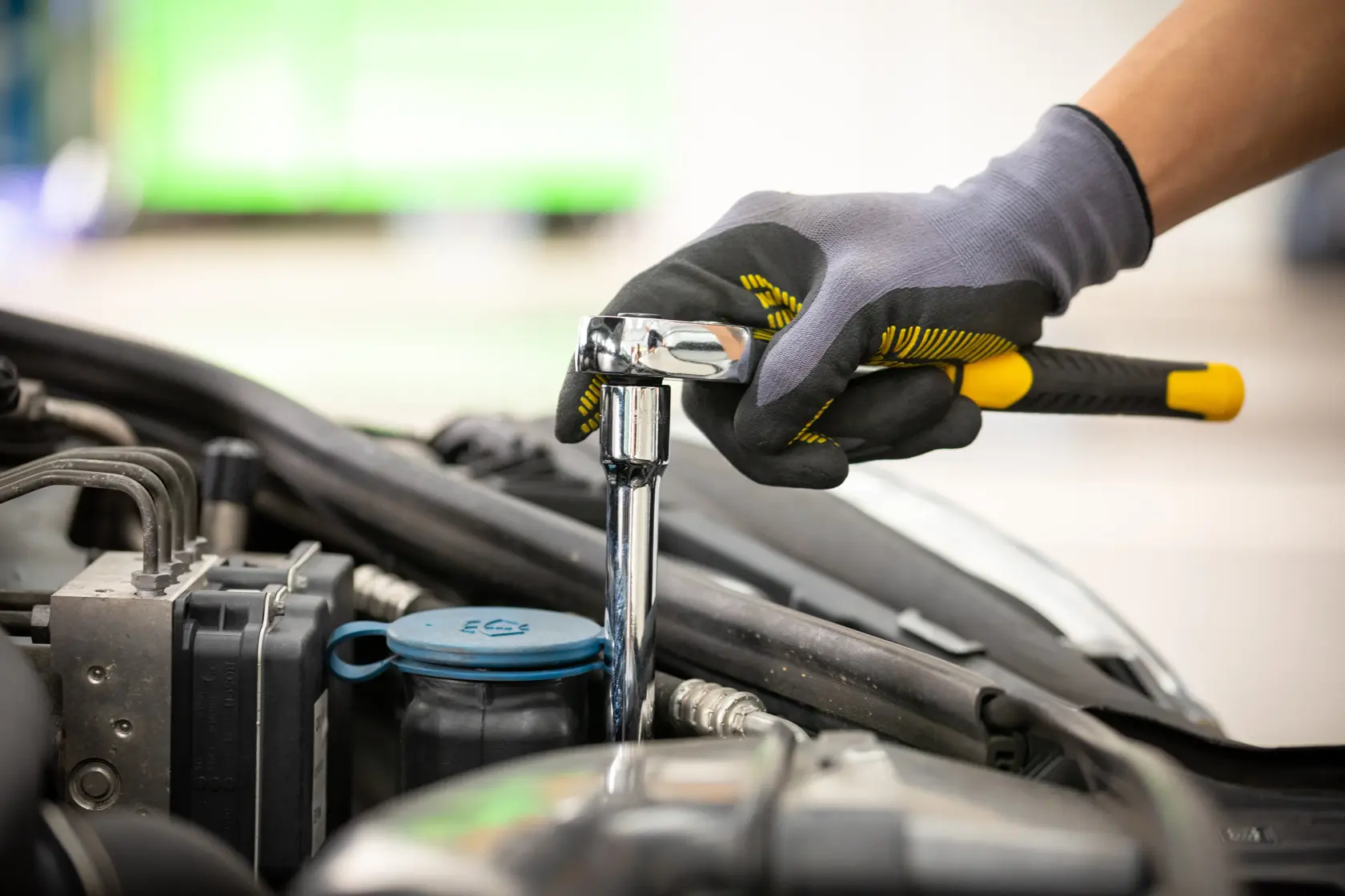 Foto des STANLEY STMT88941-0 Ratschen-Schlüssels im Einsatz am Auto-Motor, Handschuhe getragen.