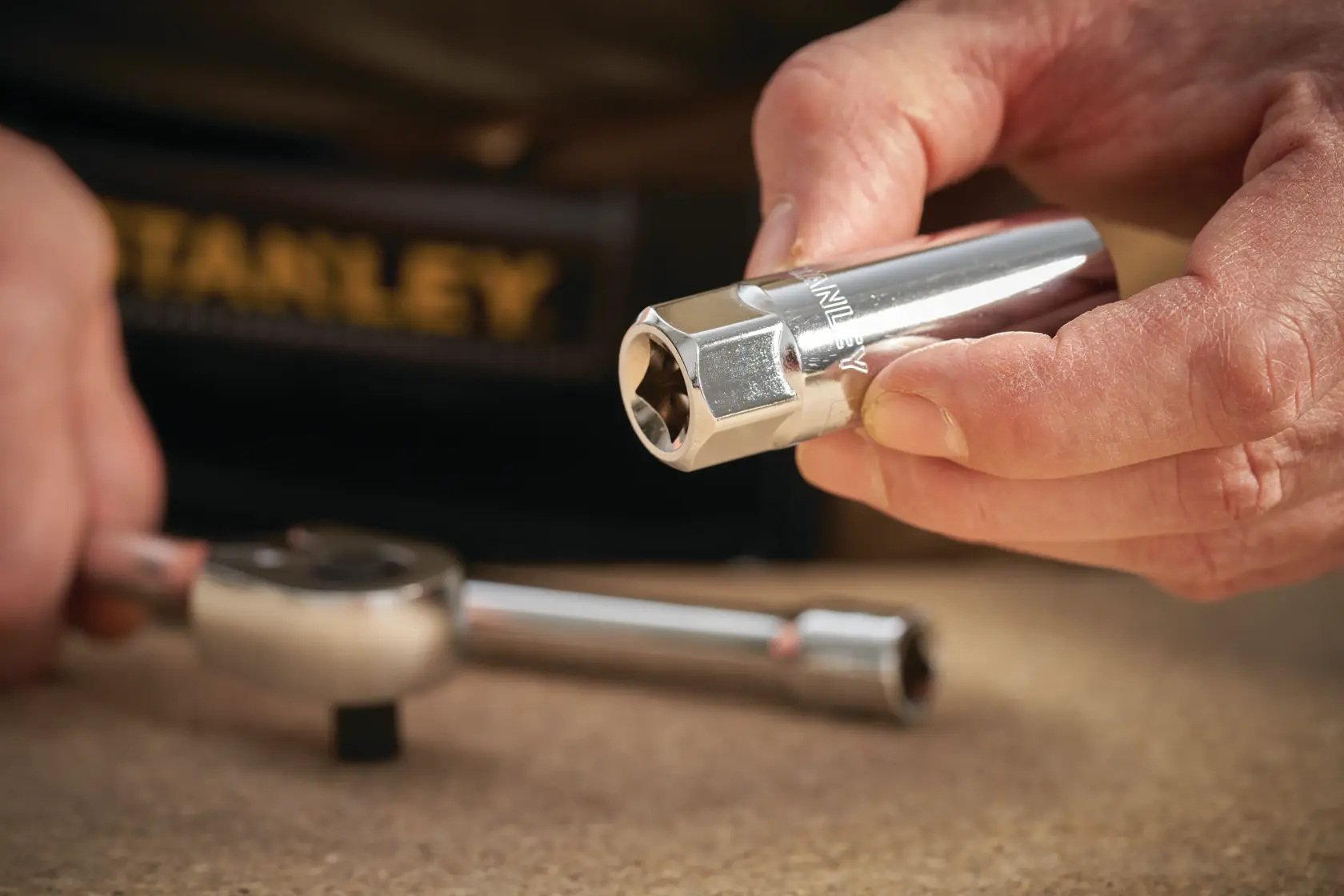 Foto des STANLEY STMT88942-0 Chrom-Steckschlüssels in der Hand, Ratschen-Schlüssel auf dem Tisch.