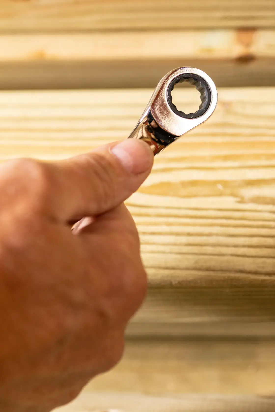STANLEY STMT89911-0 Ratschen-Schlüssel in der Hand, Nahaufnahme, Hintergrund aus Holz.
