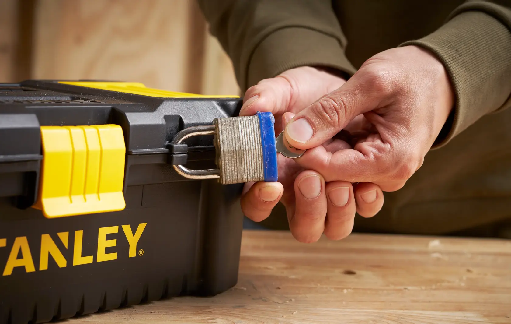 Foto der STANLEY STST1-75514 Werkzeugbox mit gelbem Verschluss, Person öffnet Vorhängeschloss.
