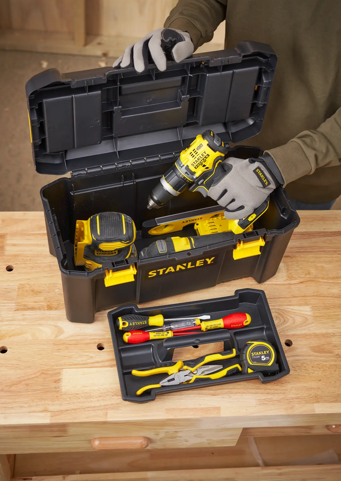 STANLEY STST1-75520 Werkzeugkasten mit gelb-schwarzen Werkzeugen, Bohrmaschine, Maßband und Handwerkzeugen.