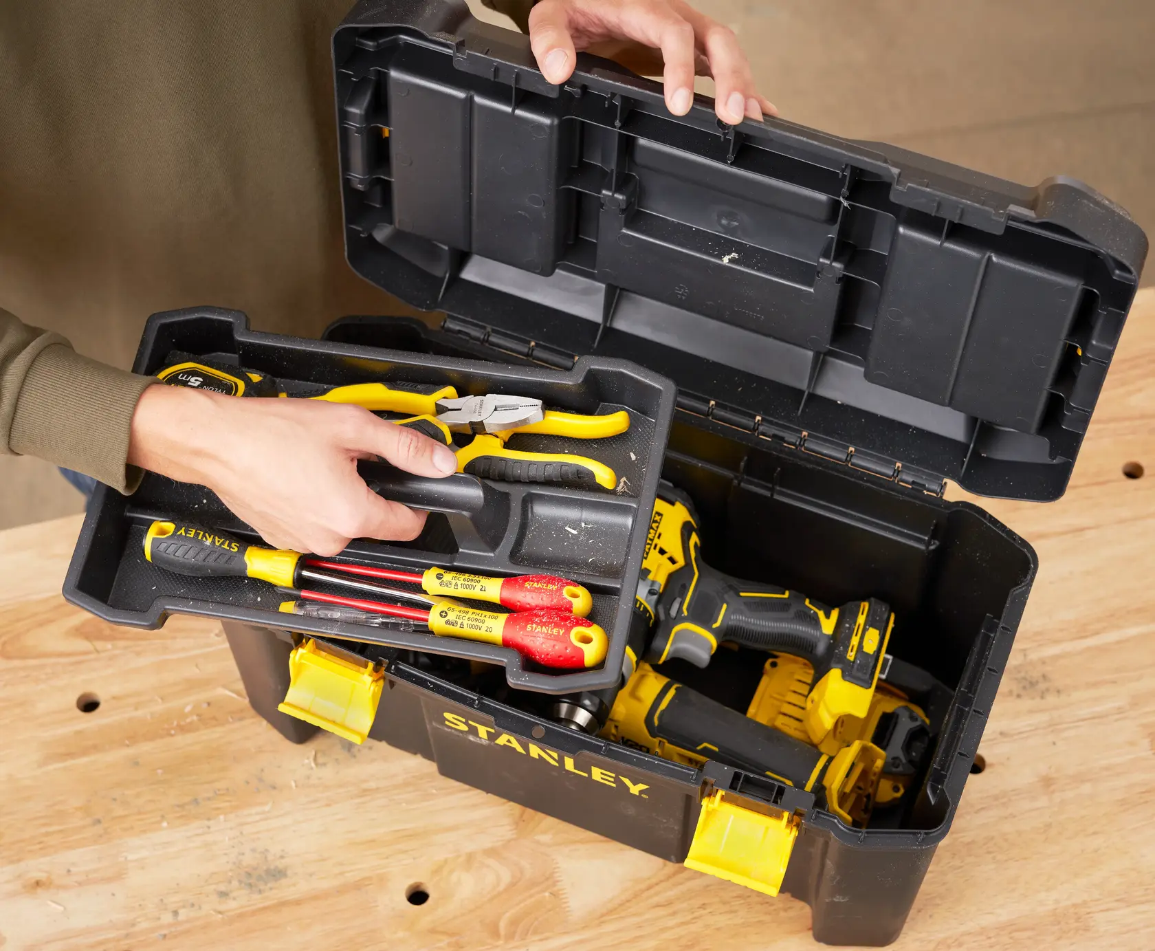 STANLEY STST1-75520 Werkzeugbox mit Handwerkzeugen und Bohrmaschine auf Werkbank, Draufsicht.