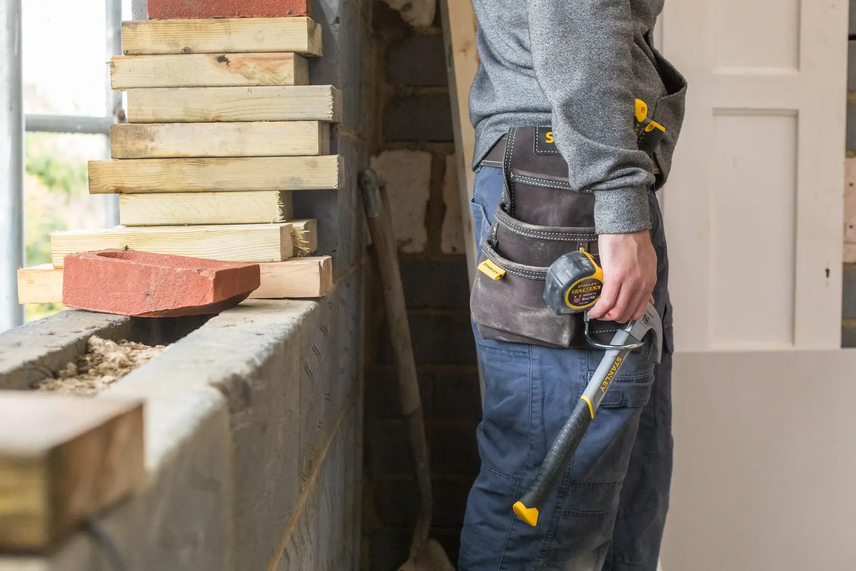 STANLEY STST1-80114 Werkzeuggürtel mit Maßband und Hammer an Bauarbeiter auf Baustelle.