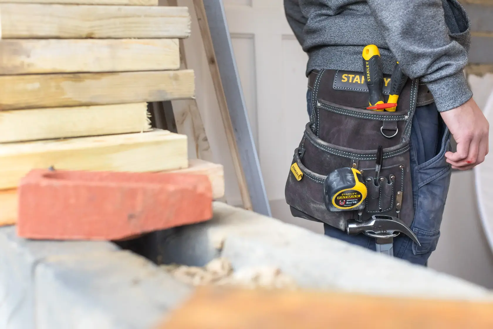 STANLEY STST1-80114 Werkzeug-Gürtel mit Maßband, Zange und Hammer, getragen auf Baustelle.