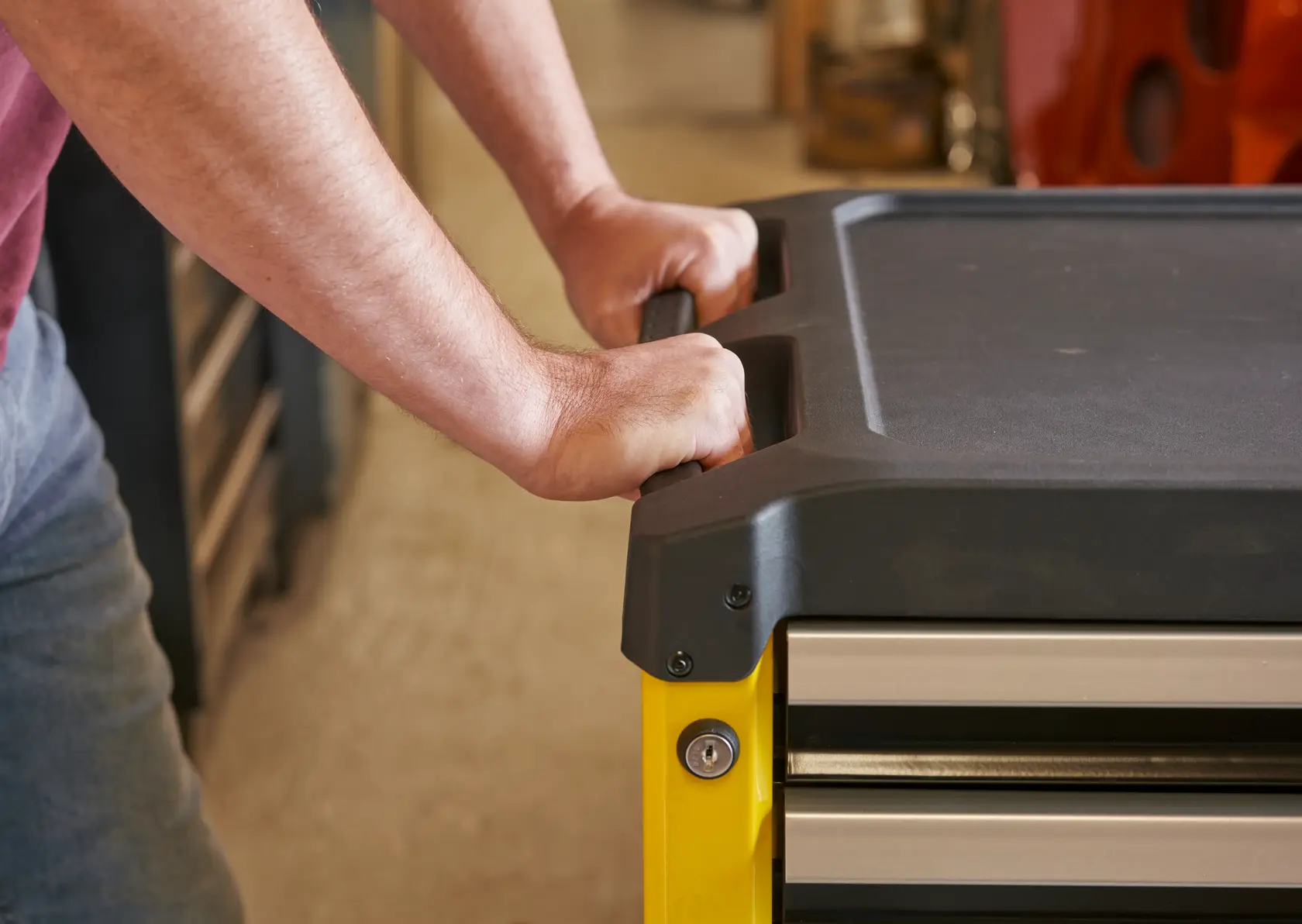 STANLEY STST74305-1 Werkzeugkisten-Griff Detail, gelber Rahmen, schwarze Oberseite, Person, Werkstatt.