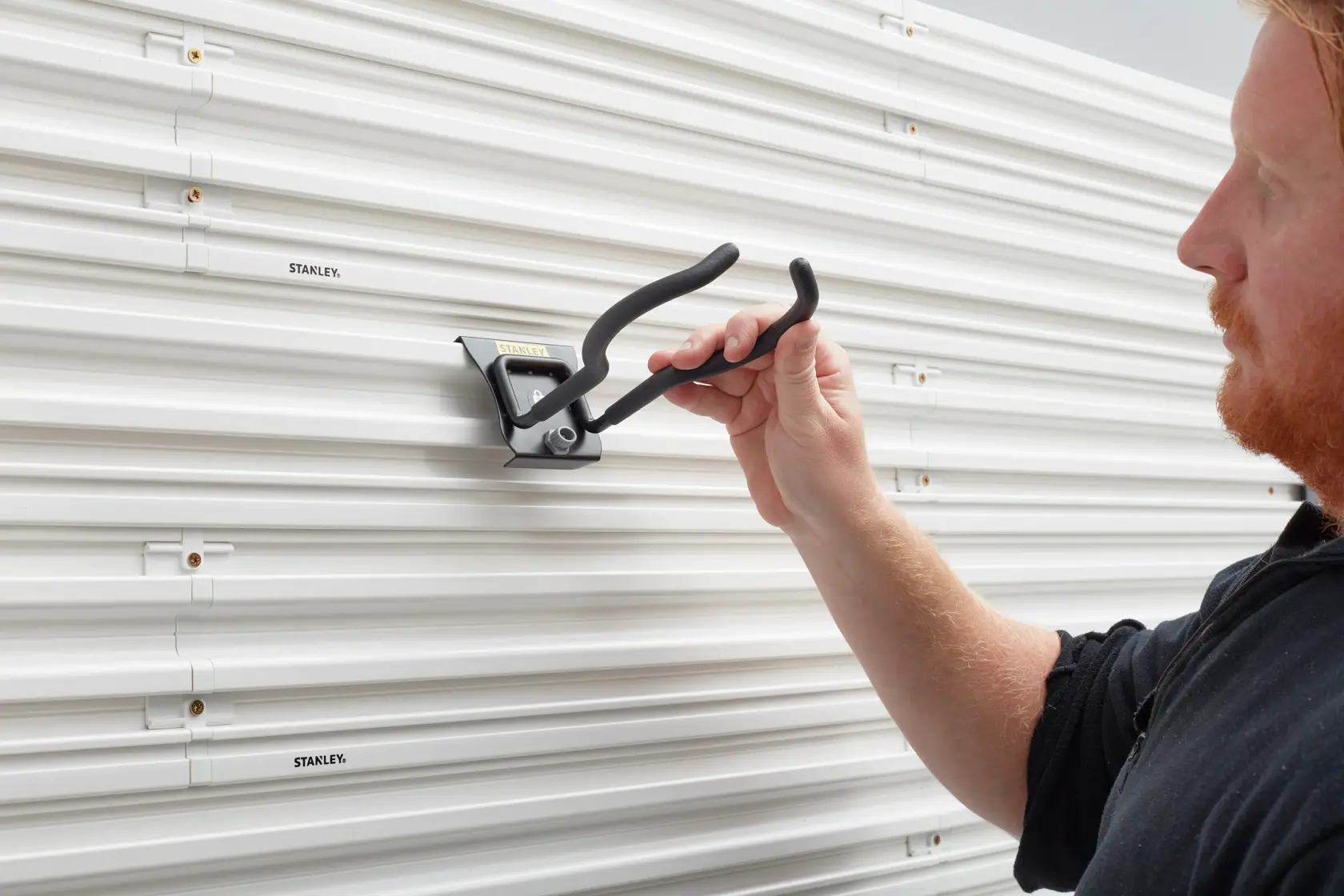 STANLEY STST82609-1 Wandhaken wird an einer weißen Lamellenwand montiert.