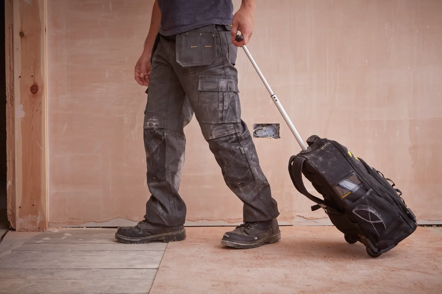 STANLEY STST83307-1 Rollwerkzeugtasche vom Arbeiter gezogen, Baustelle, Produkt Seitenansicht.